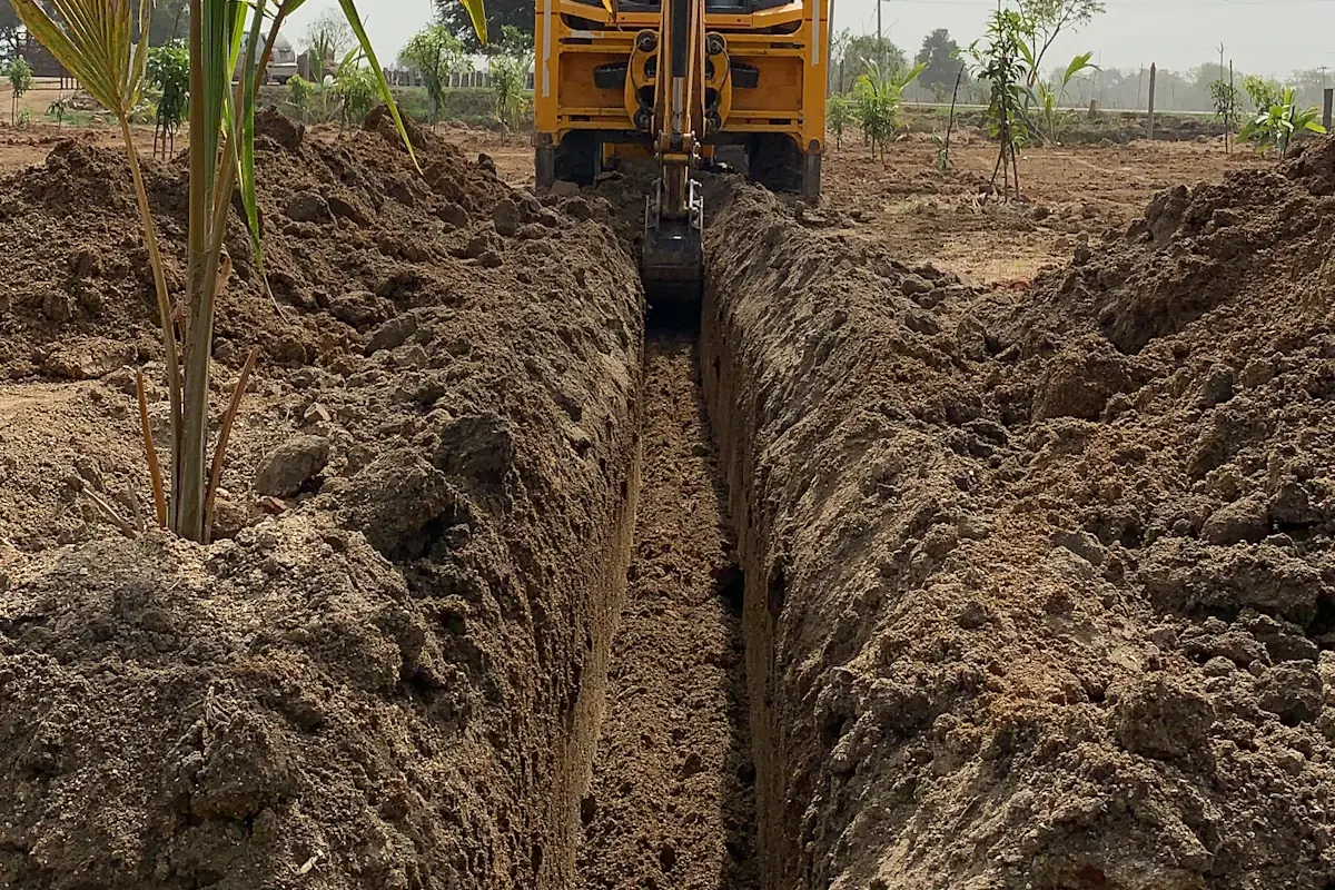 Narrow trench dug across a yard by a small excavator to reach a buried water line